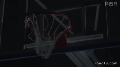 职业篮球运动员在黑暗篮球场篮球比赛中扣篮的特写图像.